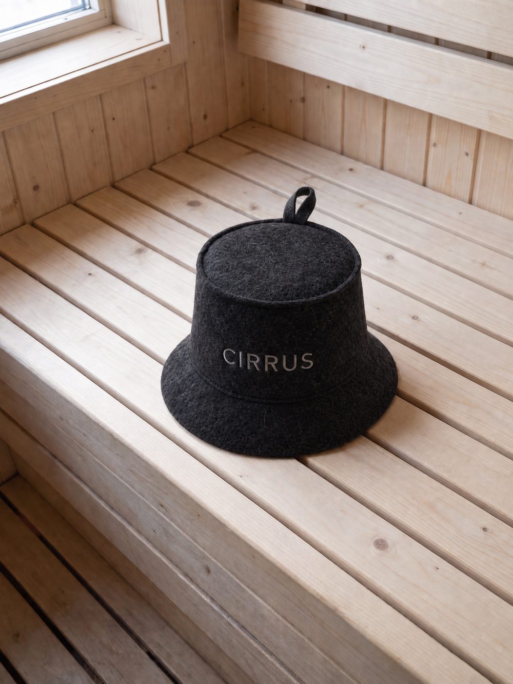 Near-black wool sauna bucket on a pine bench